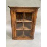 A Batheasten oak and glazed single door hanging corner cupboard, damage to the cornice