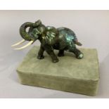 A Chinese carved mineral specimen figure of an elephant, its trunk raised together with a plinth,