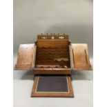 An Edwardian oak stationery rack having a flip open top with perpetual calendar, the two door fall