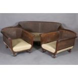 A walnut bergere caned suite, c.1910-15 having an encircling frame carved with laurel lead, double