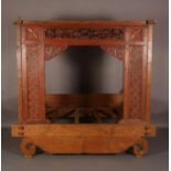 A Balinese bed, the frame having a red and black stained facade carved and pierced with a panel of