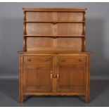 An Ercol pale elm dresser and rack, having two shelves above two drawers and two door cupboard below
