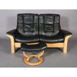 A Stressless black leather and beech reclining swivel two seater sofa with matching footstool