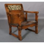 An oak monk's chair c.1920s having a fold down foliate carved panel back, hide seat, on square