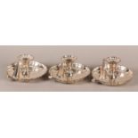 A SET OF THREE 19TH CENTURY PLATED ON COPPER CHAMBERSTICKS with snuffers, dished and fluted base