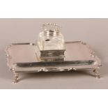 AN EDWARD VII SILVER INKSTAND of rectangular form on four hoof feet, the glass well with silver