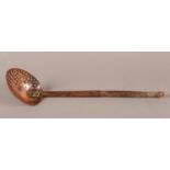 A LATE 18TH/EARLY 19TH CENTURY COPPER FOOD STRAINING SPOON on a copper and wood handle, 41cm long