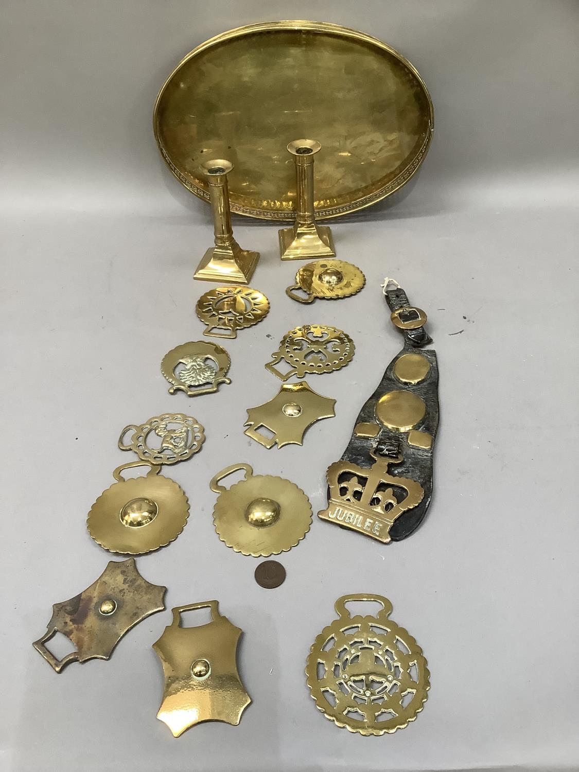 A quantity of mainly 19th century horse brasses, strung on a leather strap, including Victoria's