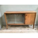 A 1970's walnut and glazed bookcase cupboard on square legs having a single door cupboard and a