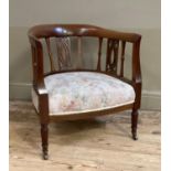 A mahogany tub chair having an open pierced back, upholstered seat and on turned legs with castors
