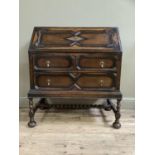 A 1920's oak Jacobean style bureau having a fall front, the interior fitted with pigeon holes and