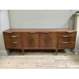 A 1970's McIntosh teak sideboard having a two door cupboard to the centre flanked by drawers to