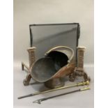A pair of cast iron fire dogs, a copper coal scuttle, two brass pokers and a modern mesh fire screen