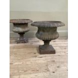 A pair of Victorian cast iron garden urns having egg and dart borders and lower reeded bodies, on
