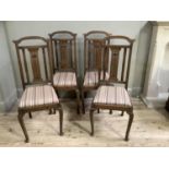 A set of four Arts and Crafts oak dining chairs, each having a semi arched top rail over a splat