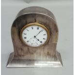 A George V silver faced clock case of arched outline, inset with an enamel face clock movement