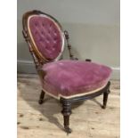 A Victorian walnut nursing chair having a carved and moulded oval back with buttoned velvet