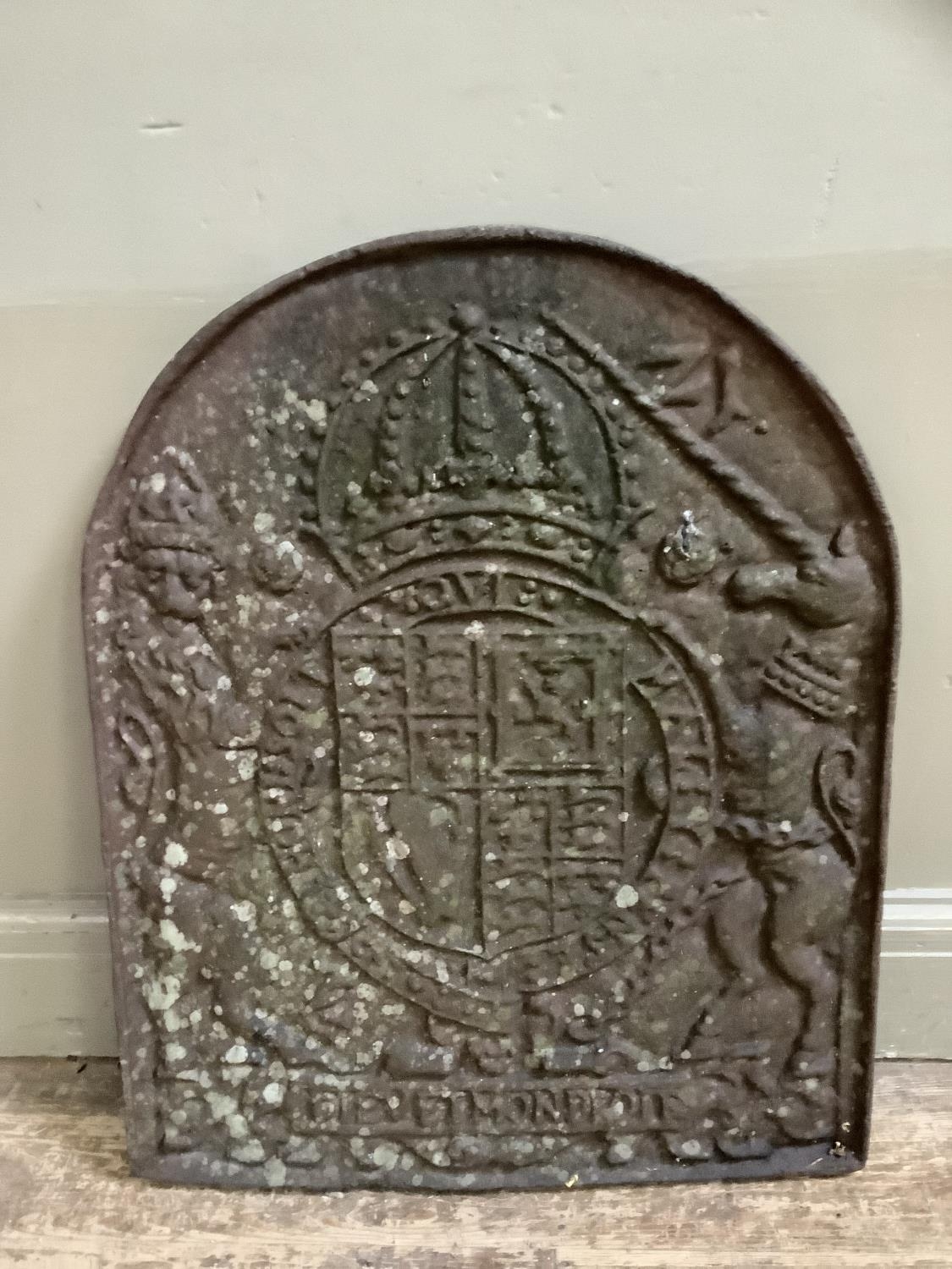 A cast iron fire back of arched outline cast with a crowned coat of arms flanked by lion and unicorn
