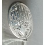 A George V oval silver locket, foliate scroll engraved to the front with open cartouche,