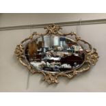 An oval bevelled wall mirror within a gilt pierced foliate surround, approximately 63cm by 91cm