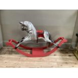 A reproduction rocking horse, grey dappled with red leather saddle and on a red bow base