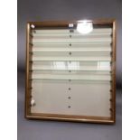 A glazed wall mounted display cabinet of narrow proportions with glass shelves, 76cm wide x 9cm deep