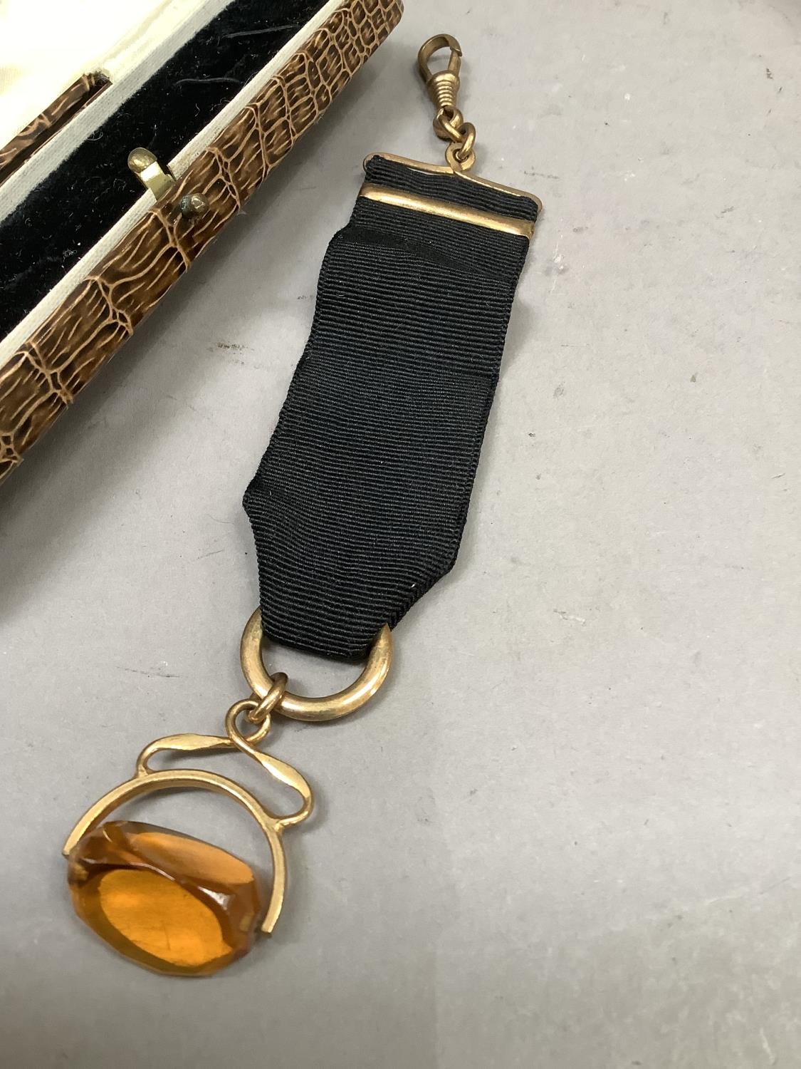 A George V pocket watch fob ribbon with swivel fastener, amber paste and rolled gold fittings