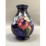 A Moorcroft pottery vase of iris pattern, tube lined and painted in mauve and green on a blue