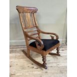 A 19th century satin beech rocking chair with black upholstered seat