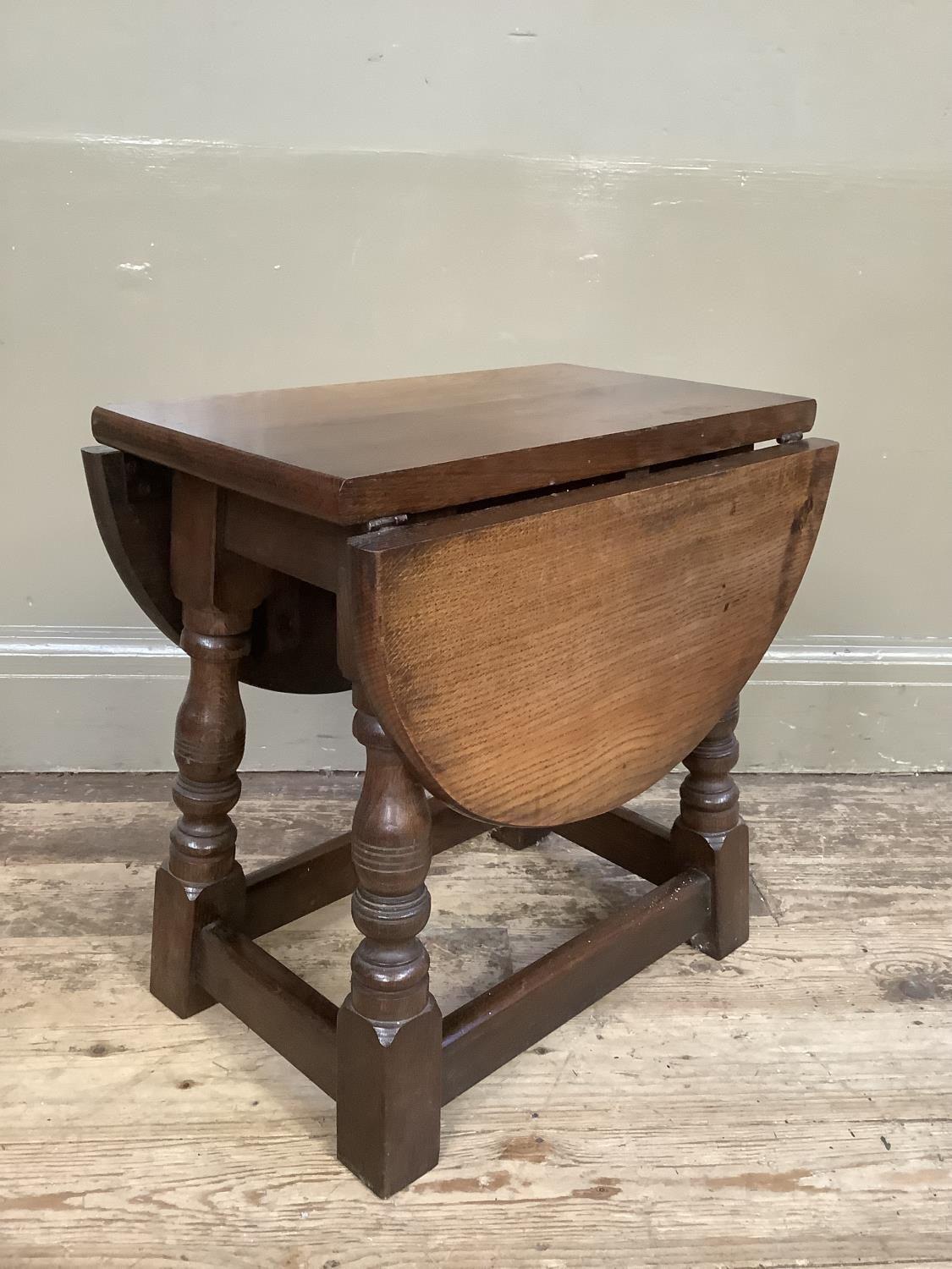 An oak oval occasional drop leaf table on baluster turned and square framing