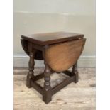 An oak oval occasional drop leaf table on baluster turned and square framing