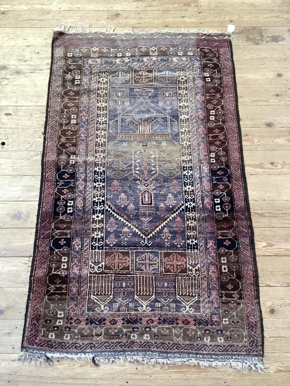 A Middle Eastern rug, the blue field woven with a stylised vase of flowers within multiple