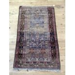 A Middle Eastern rug, the blue field woven with a stylised vase of flowers within multiple