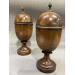 A pair of treen lidded urns, the domed covers with bud finials, knopped pedestal and circular