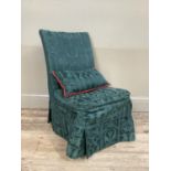 A low set single chair with green upholstered fabric cover and pillow