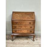 A reproduction walnut bureau having a fall front with fitted interior over three drawers and on