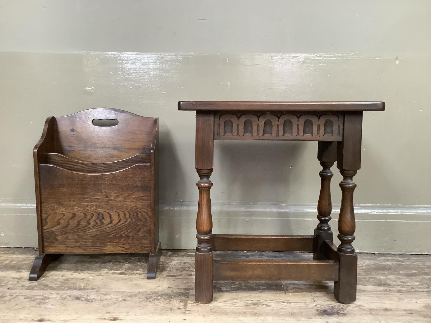 An early 20th century oak magazine rack with finger grip on refectory supports, 32cm wide by 46cm