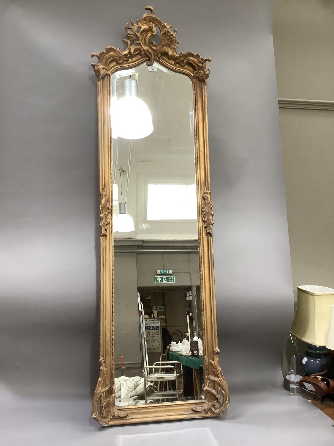 A gilt plaster framed wall mirror of 18th century design having a bevelled glass, 173cm high by 52cm