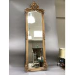 A gilt plaster framed wall mirror of 18th century design having a bevelled glass, 173cm high by 52cm