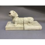 A pair of ceramic bookends modelled as a sausage dog sitting upon a book, incised signature,