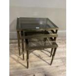 A nest of three smoked glass and gilt metal coffee tables
