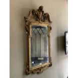 A gilt wall mirror of mid 18th century design having broken pediment and foliate shell cresting