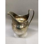 A George III silver cream jug of helmet shape, bright cut engraved border of leaf and oval motif,