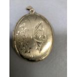 A locket in 9ct gold of oval outline, engraved to the front with a butterfly and foliage against a