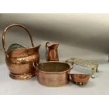 A copper coal scuttle, copper jug, planter, bowl on three feet and a brass trivet