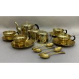 A brass tea service comprising teapot, sugar ,and cream, four cups, saucers and teaspoons
