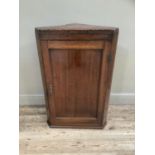 A 19th century oak hanging corner cupboard with single indented panel door