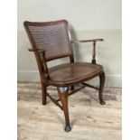 A polished beech and bergere caned open armchair