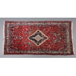 A MIDDLE EASTERN RUG, having a red abrashed ground with ivory, dark and pale blue medallion within a
