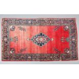 A MIDDLE EASTERN RUG HAVING A RED ABRASHED GROUND with central lozenge medallion in shades of